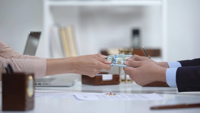 Male and female hands pulling money, dividing marital property during divorce