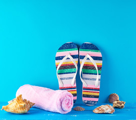 pair of female beach slippers and a pink towel on a blue background