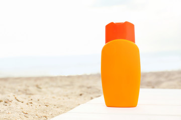 Bottle of sunscreen cream on sand beach