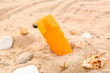 Bottle of sunscreen cream on sand beach