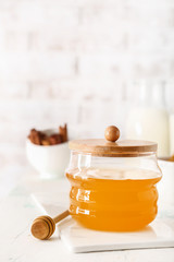 Jar with tasty honey on white table