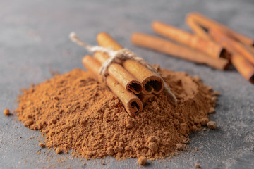 Aromatic cinnamon sticks and powder on grey background