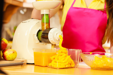 Woman making orange juice in juicer machine