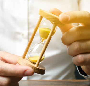 Businessman Holds Clock In Hands. Concept Of Saving Time And Money. Time Management. Planning Work. Reduced Cost And Bureaucratic Burden. Saving Productivity. Extension Of Life. Debt / Tax Holidays