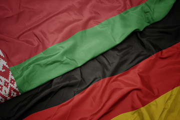 waving colorful flag of germany and national flag of belarus.