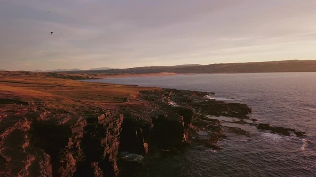 AERIAL DOLLY IN Flying over Carrowmore Lacken cliffs and rugged coast at sunset