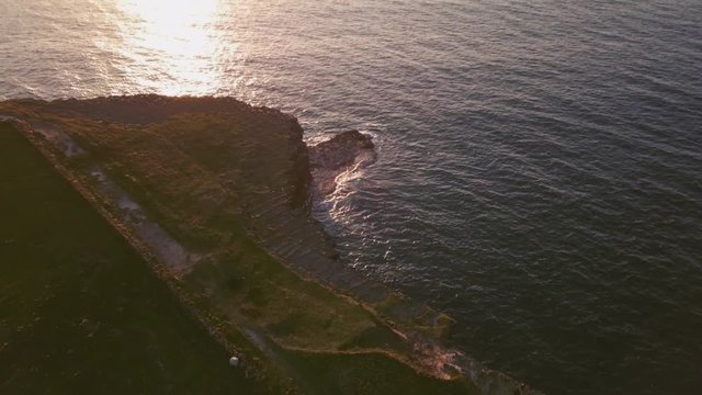 AERIAL DOLLY OUT TILT UP Revealing sunset and horizon on dramatic cliff in Ireland