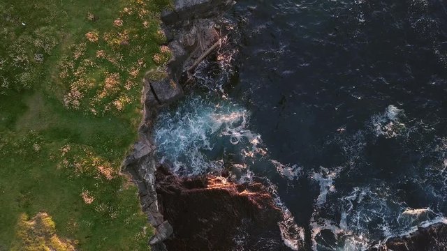 AERIAL TOP DOWN LOWERING Sea waves hitting on Carrowmore Lacken rock shelters at sunset