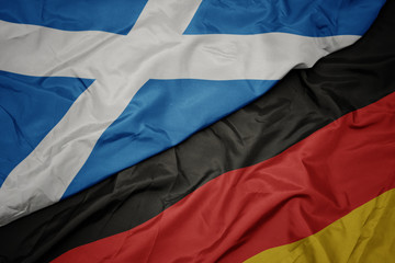 waving colorful flag of germany and national flag of scotland.