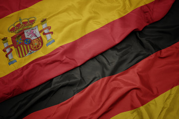 waving colorful flag of germany and national flag of spain.