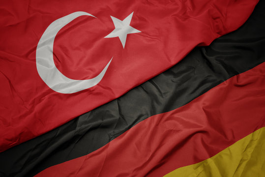 waving colorful flag of germany and national flag of turkey.