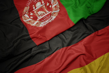 waving colorful flag of germany and national flag of afghanistan.