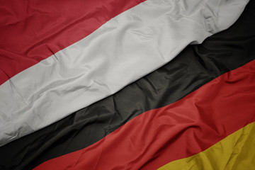 waving colorful flag of germany and national flag of indonesia.