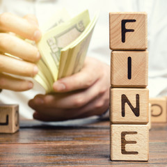 Wooden blocks with the word Fine and the man calculates the size of the fine. The concept of...