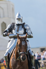 A man knight riding a brown horse over the battlefield
