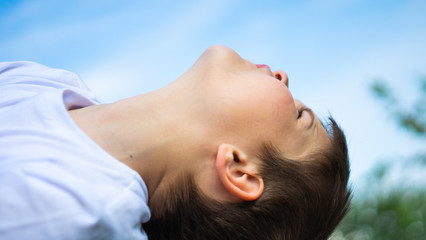 boy looking up towards blue sky and enjoying nature. Fresh air,  Imagination, freedom, environment concept