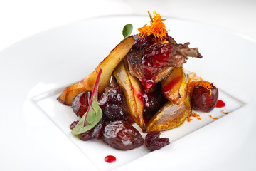 Duck leg with pear on a white plate