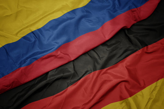 waving colorful flag of germany and national flag of colombia.