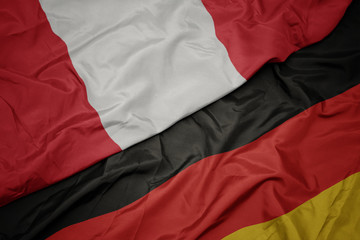 waving colorful flag of germany and national flag of peru.