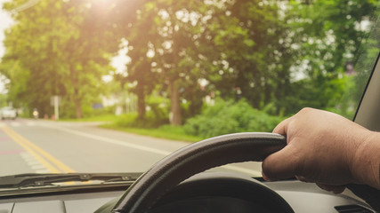 Men's hands are holding the steering wheel to drive on the road.