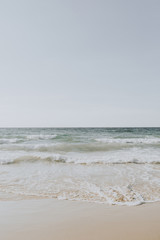 Beautiful tropical beach view with white sand and blue sea with waves on Phuket, Thailand. Minimal composition with neutral colors. Summer concept. Natural background.