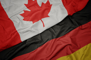 waving colorful flag of germany and national flag of canada.