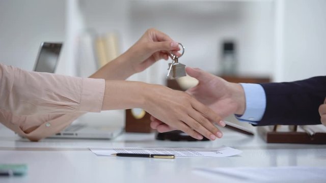 Woman signing real estate purchase agreement, taking house keys from lawyer