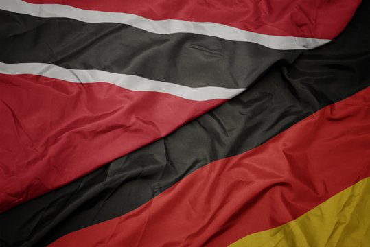waving colorful flag of germany and national flag of trinidad and tobago.