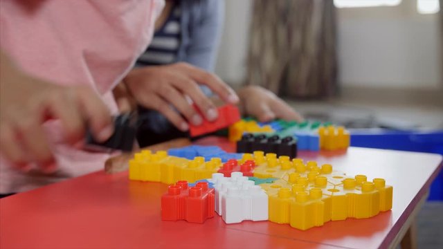 A closeup shot of young Indian kid playing with building blocks at home with his mother. 
