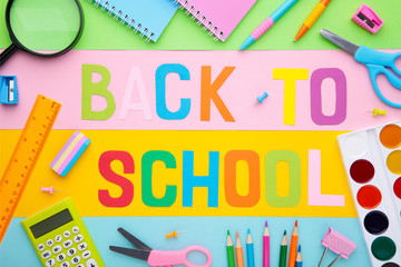Inscription Back To School with school supplies on colorful background