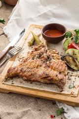 Chicken tobacco on a wooden Board with grilled vegetables and tomato sauce on tablecloth