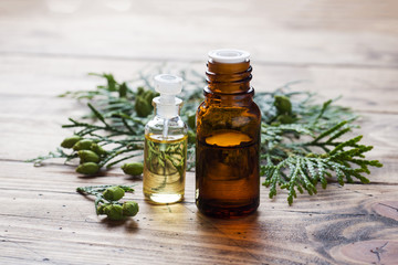 Thuja aroma essential oil in a glass jar on wooden background. Copy space. Selective focus.