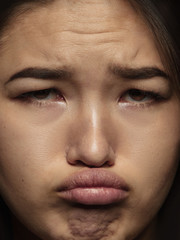 Close up portrait of young and emotional chinese woman. Highly detail photoshot of female model with well-kept skin and bright facial expression. Concept of human emotions. Looks sad, offended.