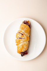 Fresh homemade croissant with cherry on plate