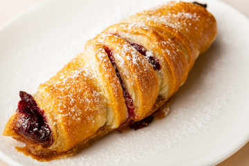 Fresh homemade croissant with cherry close-up