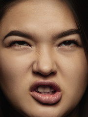 Close up portrait of young and emotional chinese woman. Highly detail photoshot of female model with well-kept skin and bright facial expression. Concept of human emotions. Angry, scaring.