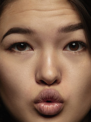 Close up portrait of young and emotional chinese woman. Highly detail photoshot of female model with well-kept skin and bright facial expression. Concept of human emotions. Sending kisses.