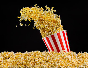 Flying popcorn from striped bucket isolated on black background