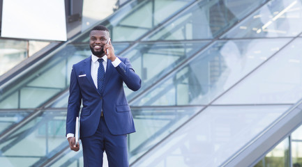 Smiling Afro Businessman Having Phone Conversation In Urban Area