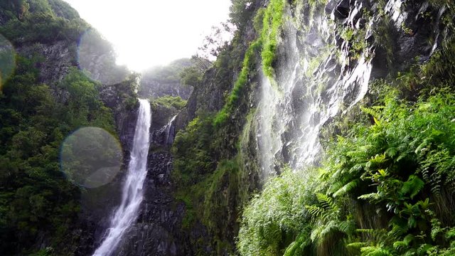 Madeira, Portugal, low angle view of Risco waterfall with sun flare