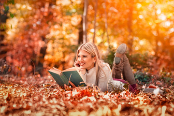 Beautiful girl with book in the autumn park