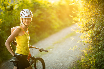 Pretty, young woman biking on a mountain bike enjoying healthy active lifestyle outdoors in summer...