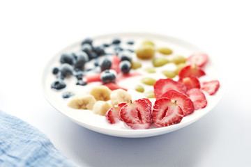 plate with vegan slices of frozen fruits: arbuk, blueberries, blueberries, banana with yogurt