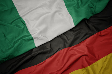 waving colorful flag of germany and national flag of nigeria.