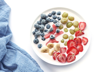 plate with vegan slices of frozen fruits: arbuk, blueberries, blueberries, banana with yogurt