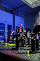 Quantum optics lab installations with laser, irises, appertures - laser reflect on optic table un...