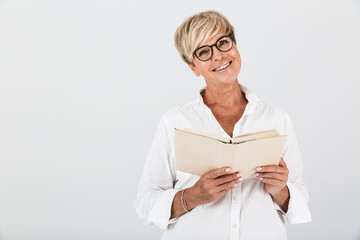 Portrait of joyous middle-aged woman wearing eyeglasses reading book