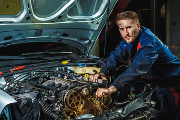 Close up hands of unrecognizable mechanic doing car service and maintenance. Mechanic working in...