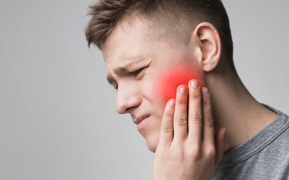Man suffering from toothache, touching inflamed cheek