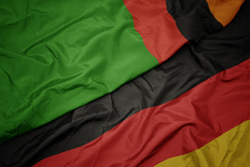 waving colorful flag of germany and national flag of zambia.
